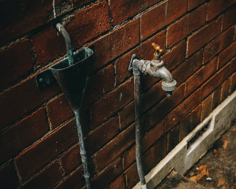 Close-up of a rusty outdoor faucet attached to a weathered brick wall.