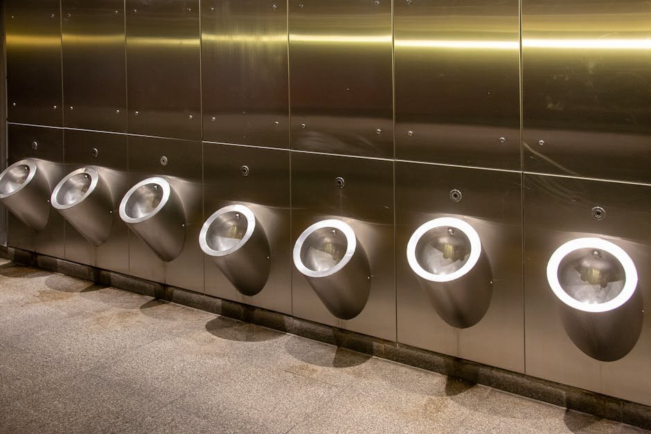 Row of modern stainless steel urinals in a public bathroom, clean and minimalistic design.